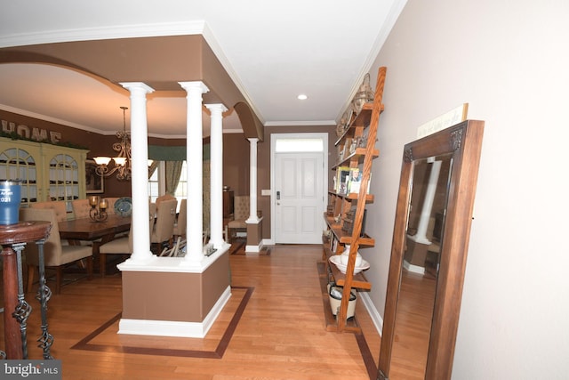 entrance foyer featuring hardwood / wood-style flooring, an inviting chandelier, decorative columns, and crown molding