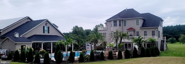 back of property featuring a fenced in pool and a lawn