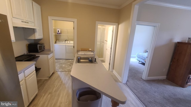 kitchen featuring white cabinets, sink, light hardwood / wood-style flooring, washer and dryer, and ornamental molding