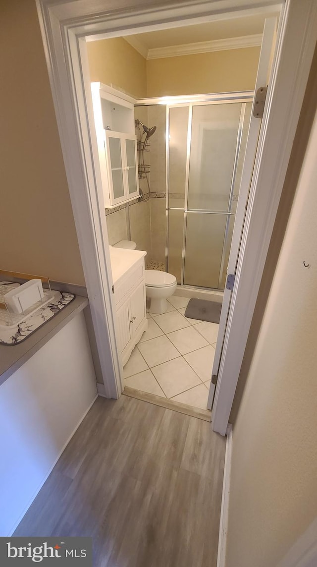 bathroom featuring walk in shower, hardwood / wood-style floors, toilet, vanity, and ornamental molding