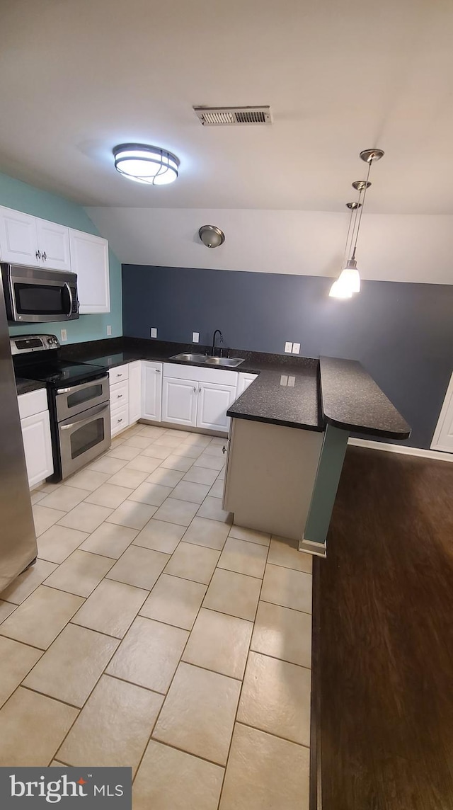 kitchen with white cabinets, sink, hanging light fixtures, light tile patterned floors, and stainless steel appliances