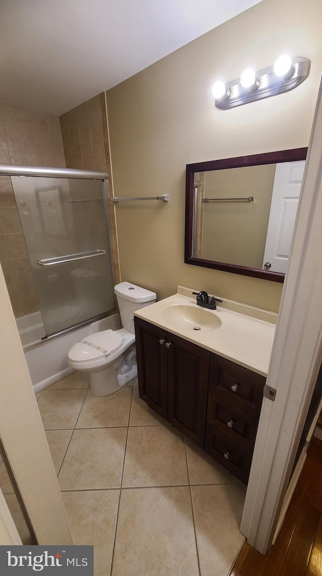 full bathroom featuring tile patterned floors, vanity, enclosed tub / shower combo, and toilet