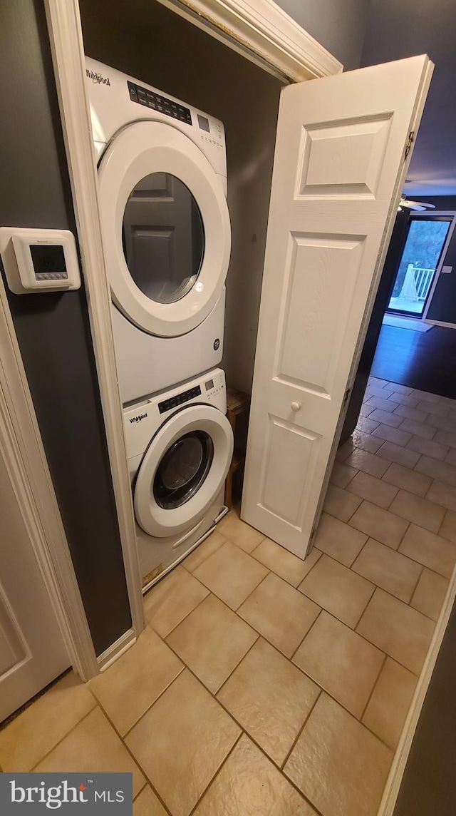 laundry room featuring light tile patterned flooring and stacked washer and dryer