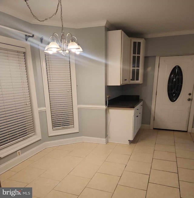 kitchen with an inviting chandelier, white cabinets, crown molding, hanging light fixtures, and light tile patterned flooring