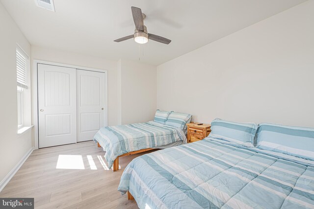 bedroom with ceiling fan, a closet, and light hardwood / wood-style floors