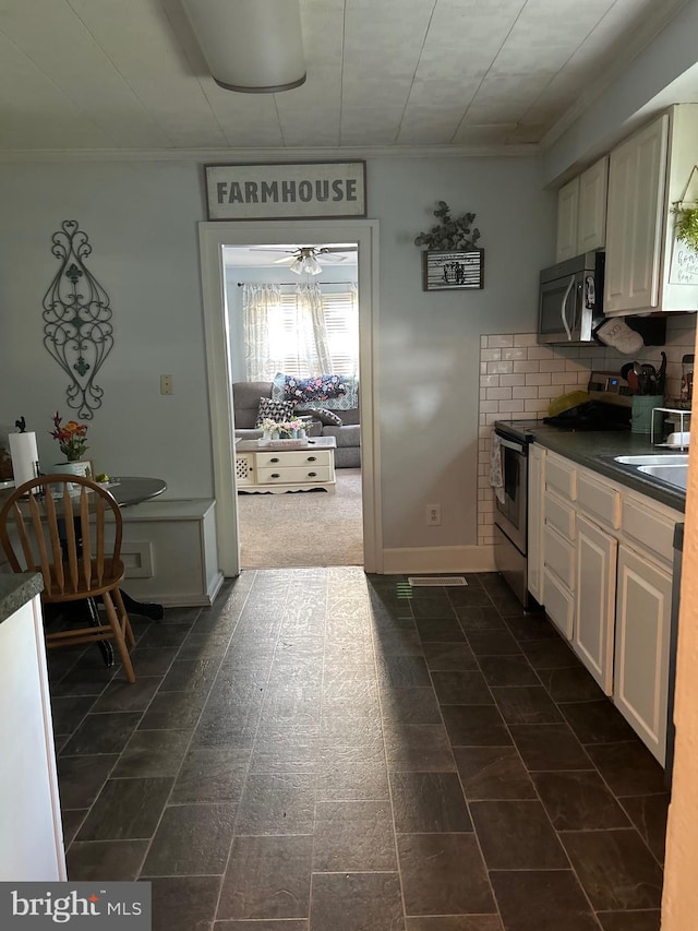 kitchen featuring ornamental molding, a sink, dark countertops, appliances with stainless steel finishes, and decorative backsplash