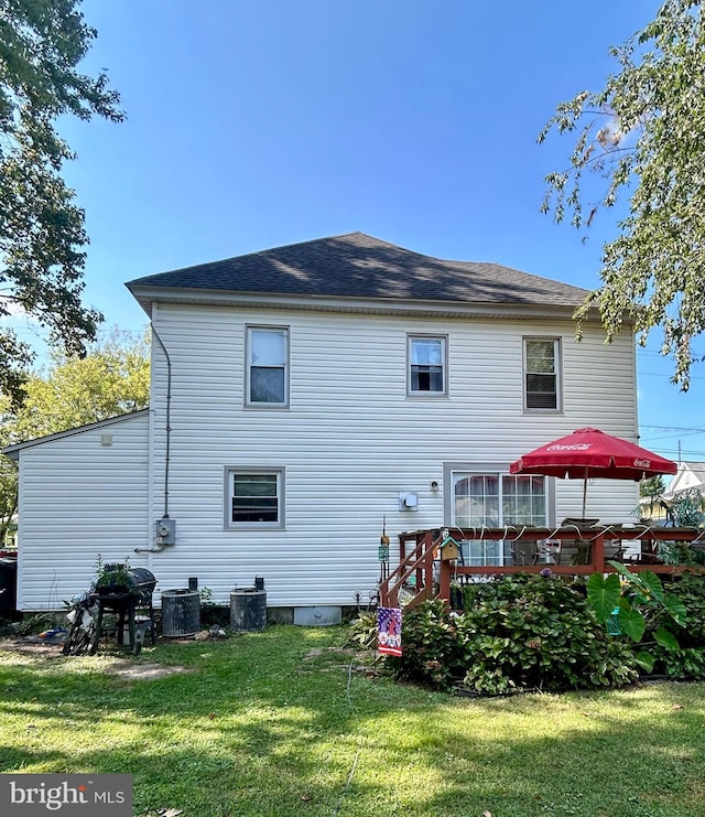 rear view of house with a wooden deck, a lawn, and central AC unit