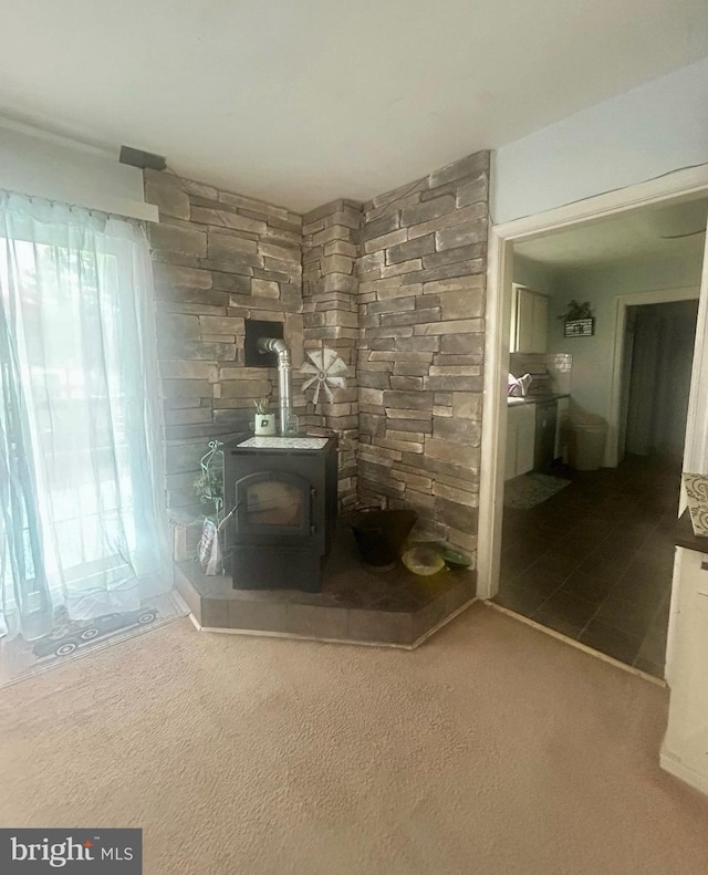 unfurnished room featuring a wood stove and carpet floors