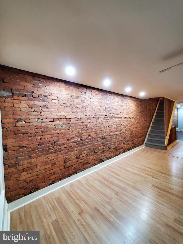 spare room with wood-type flooring and brick wall