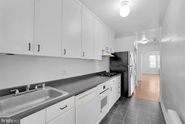 kitchen with appliances with stainless steel finishes, white cabinets, radiator heating unit, dark hardwood / wood-style floors, and sink