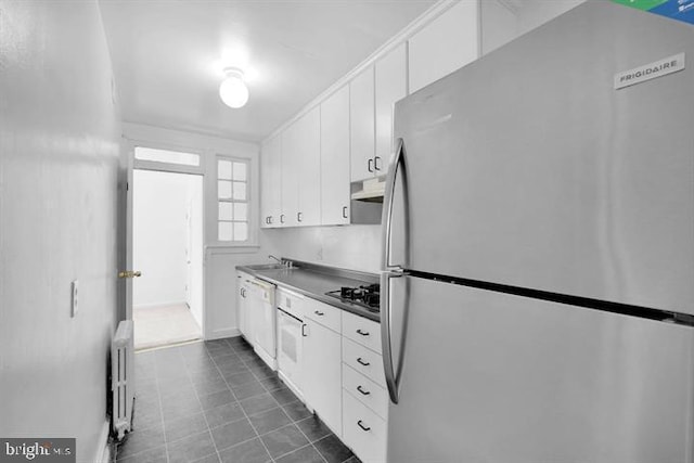 kitchen featuring appliances with stainless steel finishes, white cabinets, radiator heating unit, sink, and extractor fan