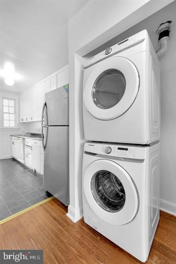 clothes washing area with dark hardwood / wood-style flooring and stacked washing maching and dryer