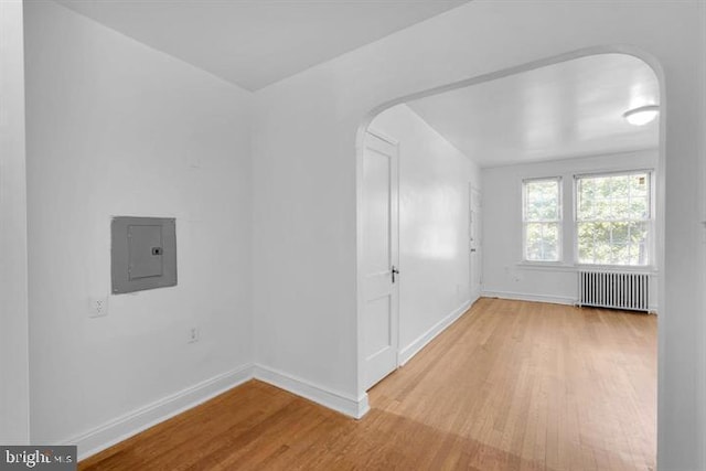 spare room featuring radiator, light hardwood / wood-style floors, and electric panel