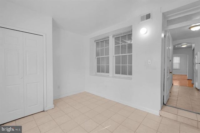 interior space with white fridge, light tile patterned flooring, and a closet