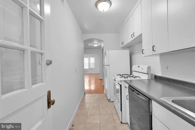 kitchen with white range, sink, white cabinets, light tile patterned floors, and stainless steel dishwasher