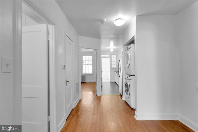 interior space with stacked washer / drying machine and light hardwood / wood-style flooring