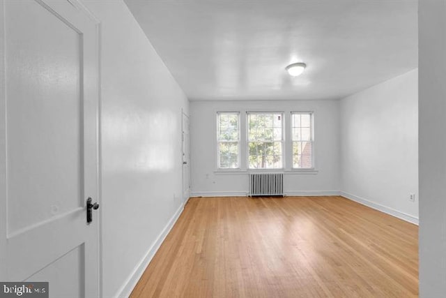 unfurnished room with radiator heating unit and light hardwood / wood-style flooring