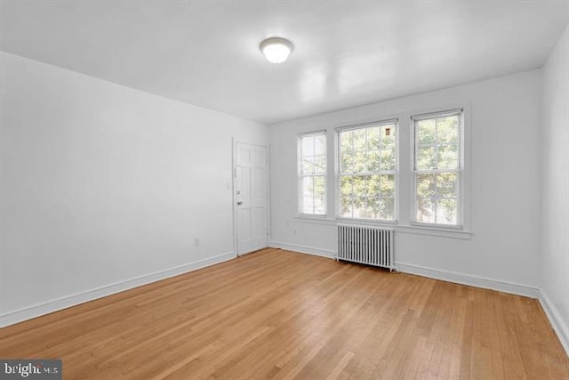 unfurnished room featuring light hardwood / wood-style floors and radiator heating unit