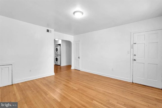 spare room with light hardwood / wood-style flooring and stacked washer / dryer