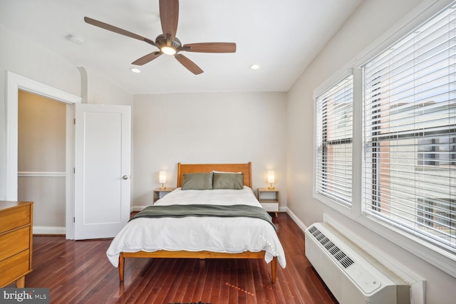 bedroom featuring dark hardwood / wood-style flooring, ceiling fan, and a wall unit AC