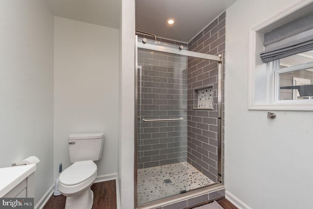 bathroom featuring hardwood / wood-style floors, vanity, toilet, and a shower with door