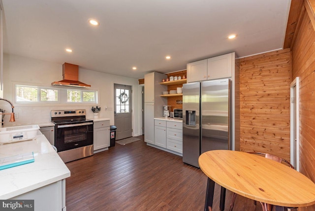 kitchen with appliances with stainless steel finishes, wooden walls, range hood, and plenty of natural light