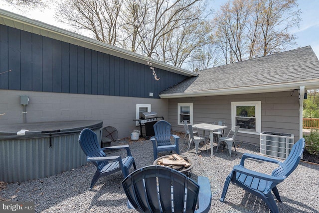 view of patio with a hot tub, central air condition unit, a fire pit, and area for grilling