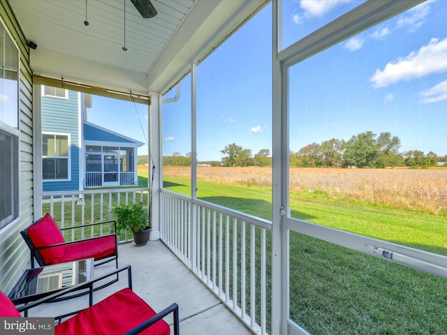 sunroom with ceiling fan, a healthy amount of sunlight, and a rural view