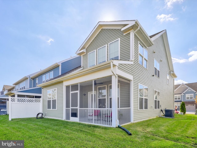 rear view of house with a sunroom, central AC unit, and a lawn