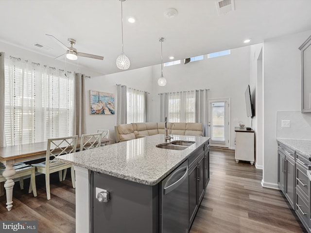 kitchen with sink, dark hardwood / wood-style flooring, stainless steel dishwasher, an island with sink, and pendant lighting