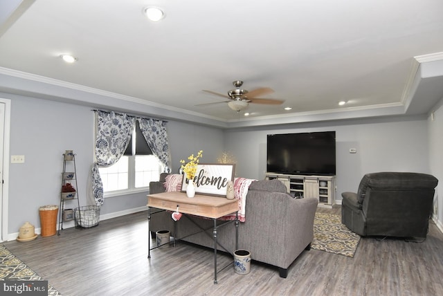 living room featuring ceiling fan, a raised ceiling, dark hardwood / wood-style flooring, and crown molding