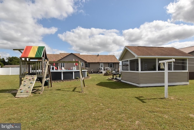 view of playground with a yard and a sunroom