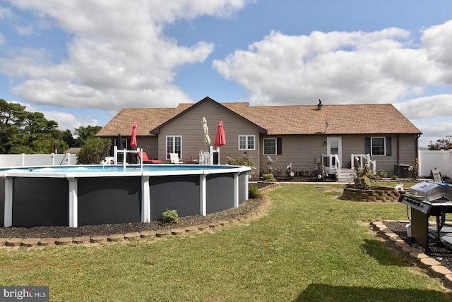 back of house with a fenced in pool and a lawn