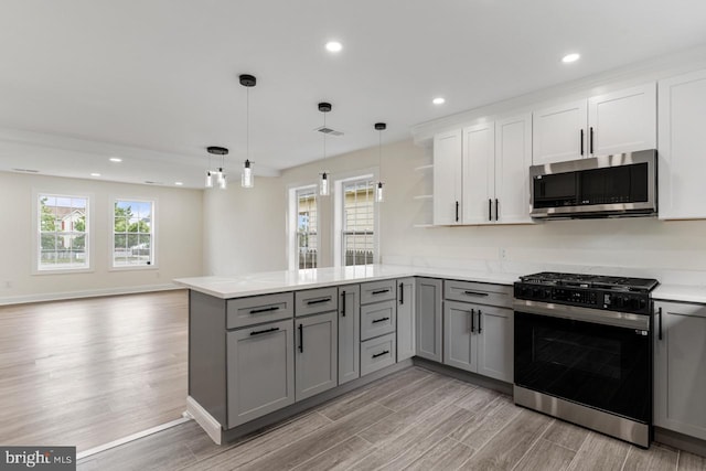 kitchen featuring white cabinetry, kitchen peninsula, gray cabinets, stainless steel appliances, and decorative light fixtures