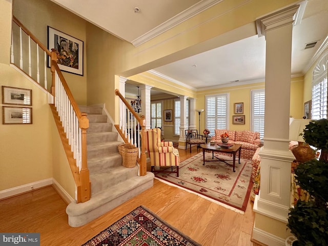 interior space with decorative columns, baseboards, stairway, wood finished floors, and crown molding