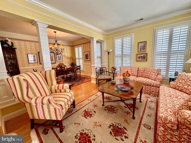 living area featuring visible vents, decorative columns, and crown molding