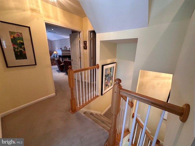 hallway with carpet flooring, an upstairs landing, and baseboards