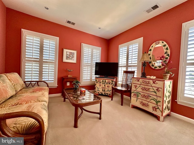 living area featuring a wealth of natural light, visible vents, and carpet flooring