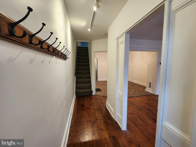 corridor with dark hardwood / wood-style flooring and rail lighting