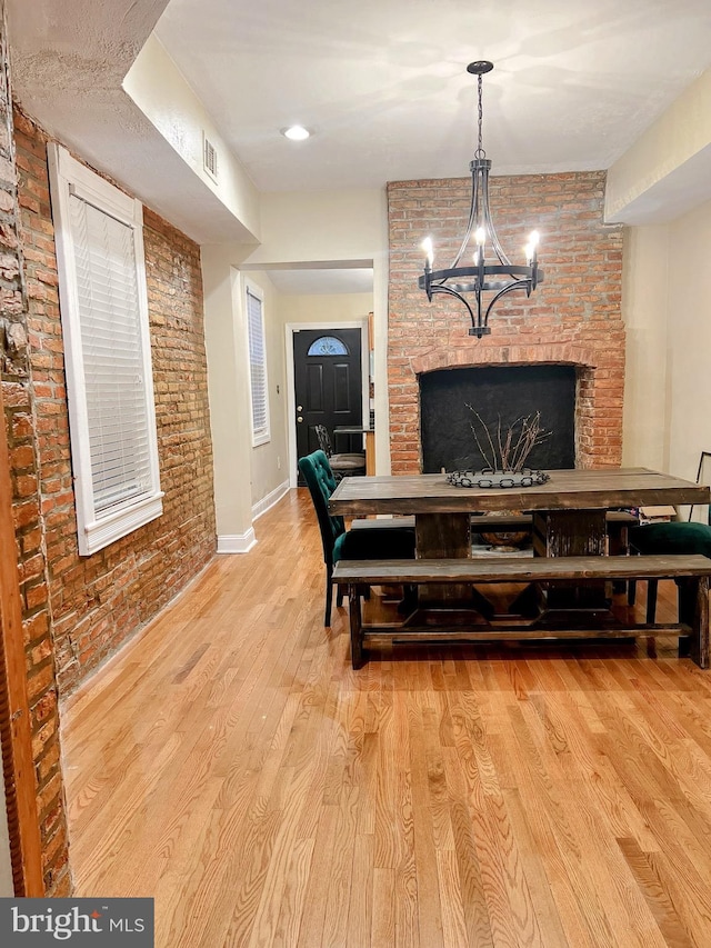 interior space with a fireplace, light hardwood / wood-style floors, and brick wall