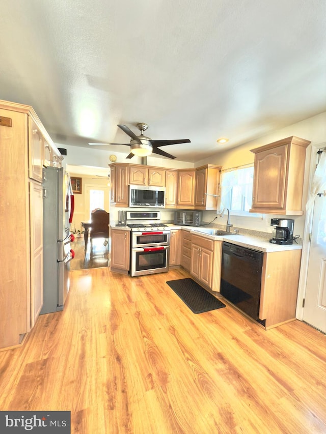 kitchen featuring sink, ceiling fan, appliances with stainless steel finishes, light hardwood / wood-style floors, and a textured ceiling