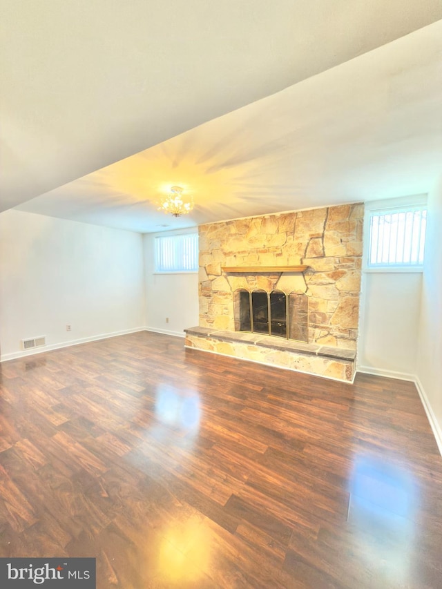 unfurnished living room featuring a stone fireplace and dark wood-type flooring