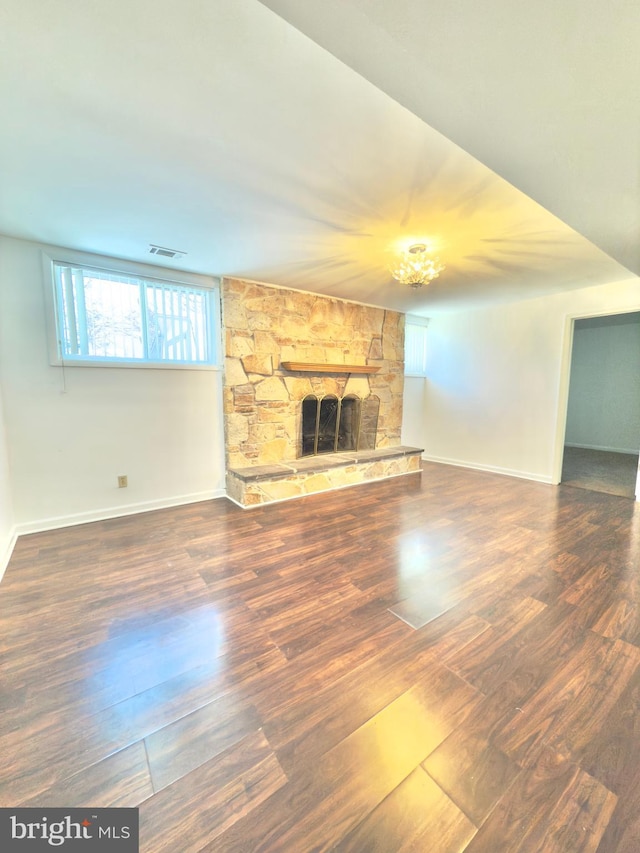 unfurnished living room with a stone fireplace and dark hardwood / wood-style flooring