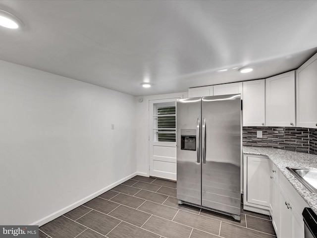 kitchen featuring appliances with stainless steel finishes, light stone countertops, white cabinetry, and backsplash