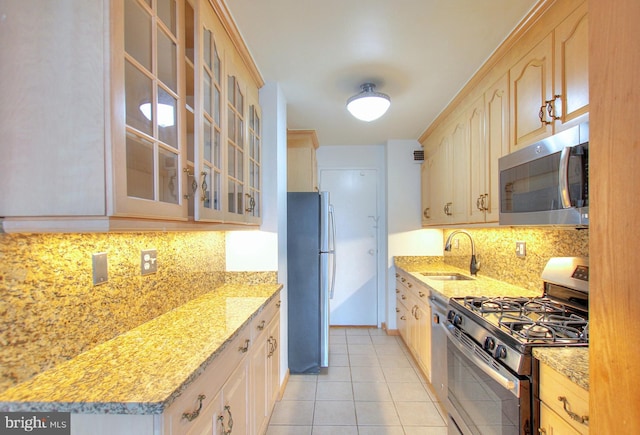 kitchen with light stone countertops, appliances with stainless steel finishes, sink, light brown cabinets, and light tile patterned flooring