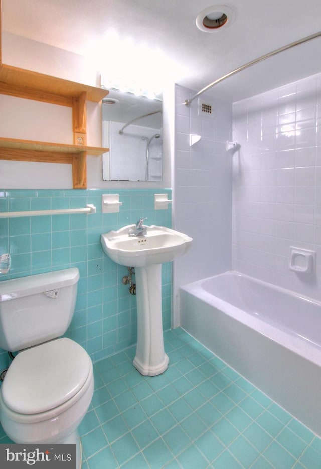 bathroom with backsplash, tile walls, toilet, tile patterned floors, and tiled shower / bath combo