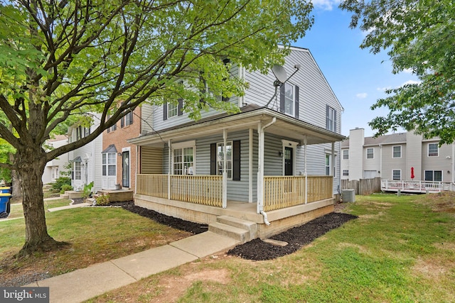 view of front facade featuring a front yard, covered porch, and central AC