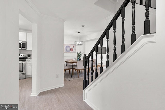 entryway featuring ornamental molding, an inviting chandelier, and light hardwood / wood-style flooring