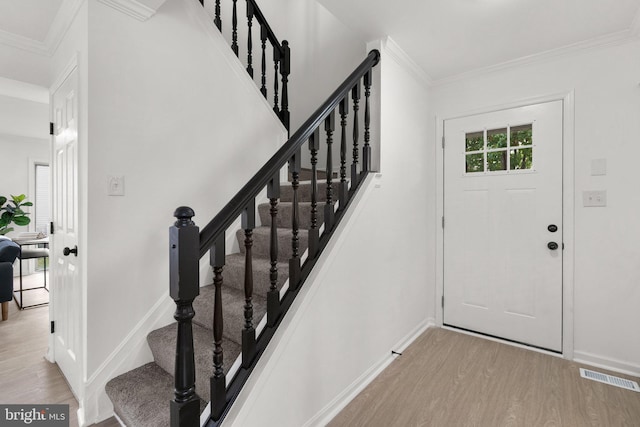 foyer with light hardwood / wood-style floors and crown molding