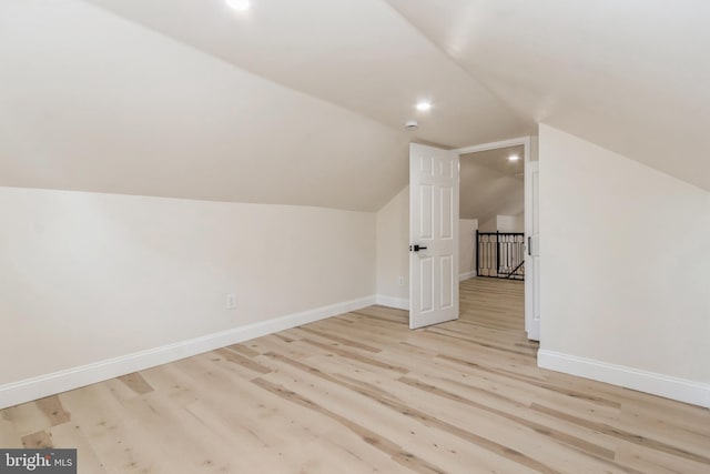 additional living space featuring light wood-type flooring and lofted ceiling